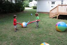 two young boys playing with beach balls in the yard