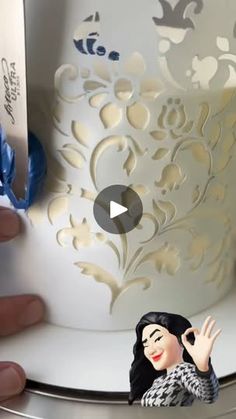 a cake being decorated with white frosting and blue decorations on it's side