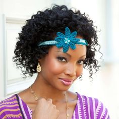 a woman with curly hair wearing a blue flower headband