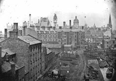 an old black and white photo of a city with lots of buildings in the background