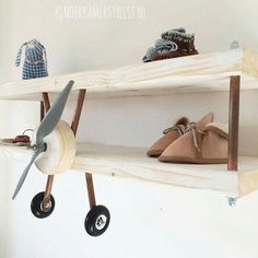 two wooden shelves with shoes on them and a toy airplane hanging from the top one