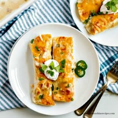 two white plates topped with enchiladas next to a blue and white towel