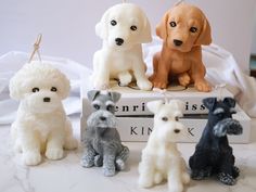 four different colored dogs sitting on top of a white table next to eachother