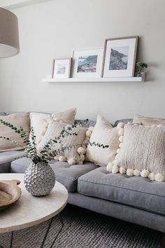 a living room with gray couches and white pom - poms on the pillows