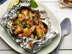 a plate topped with chicken covered in tin foil and garnished with cilantro