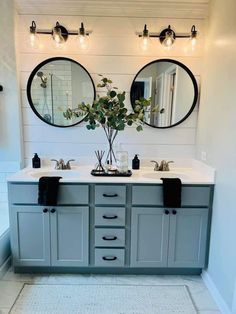 a bathroom with two sinks, mirrors and lights on the wall above them is shown