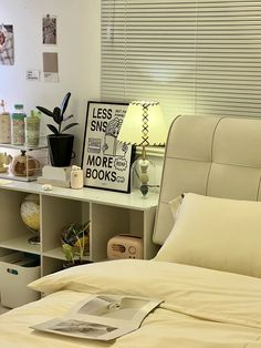 a white bed sitting in a bedroom next to a shelf filled with books and plants