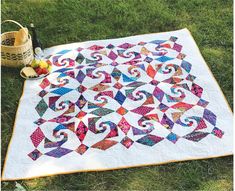 a quilt is laying on the grass next to a basket