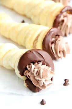 three chocolate covered banana sticks on a white surface