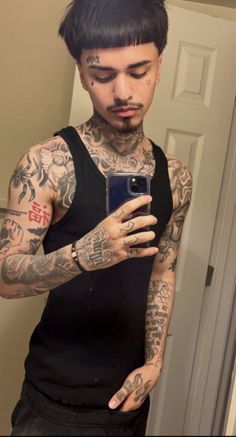 a tattooed man taking a selfie with his cell phone