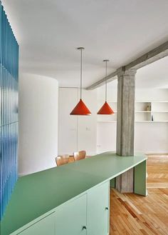 an empty room with wooden floors and green counter top in front of two red lamps