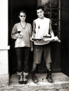 black and white photograph of two people holding plates with food in front of an open door