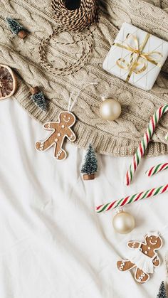 gingerbread cutouts and candy canes on a white blanket with christmas decorations around them