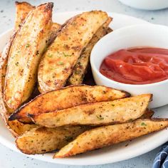 french fries on a plate with ketchup and sauce in a bowl next to it