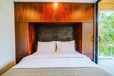 a bed with two pillows on top of it in a bedroom next to a sliding glass door