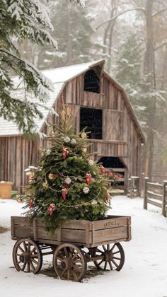 a christmas tree in a wooden wagon on a snowy day with a barn in the background