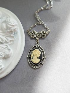 This beautiful cameo necklace features an ivory relief of a Greek Goddess on a black background. The antiqued silver pendant has an ornate design with lovely rosette details. The finishing touch is the beautiful floral necklace connector. A quintessential gift for anyone that loves Victorian cameo jewelry.  Pick your favourite colour in the drop down menu! Size: The necklace pendant is silver plated brass and measures 30 mm (1 3/16 inches) long, 21 mm (just under 1 inch) wide. Comes strung on a Silver Dragonfly Necklace, Victorian Cameo, Victorian Necklace, Cardboard Jewelry Boxes, Vintage Jewelry Art, Ornate Design, Dragonfly Necklace, Cameo Jewelry, Cameo Necklace