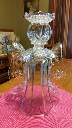 a glass candle holder sitting on top of a pink mat