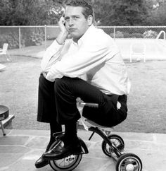 a man sitting on top of a tricycle talking on a cell phone