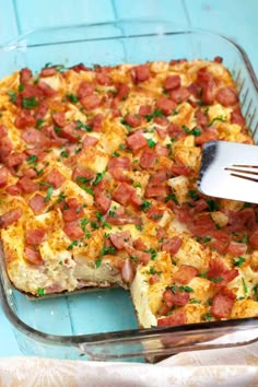 a casserole dish with ham and cheese in it being cut by a spatula