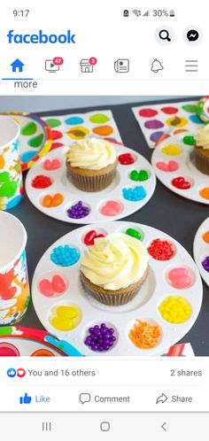 cupcakes with white frosting on plates next to paintbrushes and cups