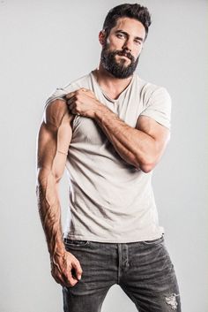 a man with a beard and no shirt is posing for the camera while wearing jeans