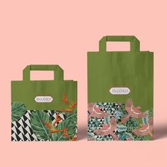 two green shopping bags with birds and palm leaves on them, against a pink background