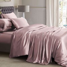 a bed covered in pink sheets and pillows