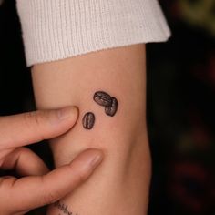 a woman's arm with two coffee beans tattooed on it