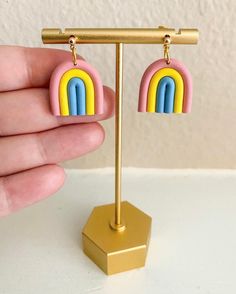 a pair of pink, yellow and blue earrings with a rainbow design hanging from them