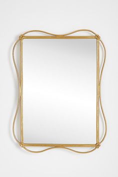 a gold framed mirror on a white wall with an intricate design around the edges and sides