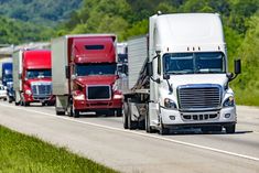 several semi trucks are lined up on the highway