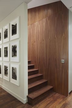 there are pictures on the wall and stairs in this living room with wood flooring