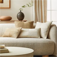 a living room with a couch, coffee table and vase on top of the sofa