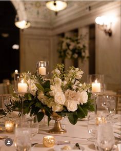 a centerpiece with white flowers and greenery on a table at a wedding reception