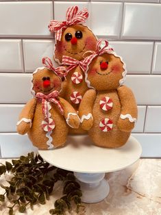 three gingerbread men are sitting on a cake plate with candy canes in their hands