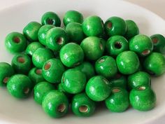 a white bowl filled with green wooden beads