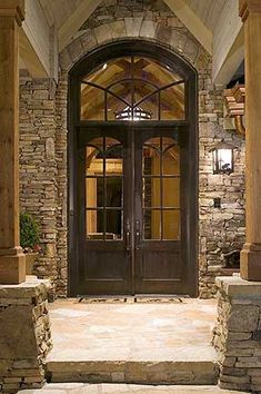 the entrance to a home with stone pillars and arched glass doors that lead into an entryway