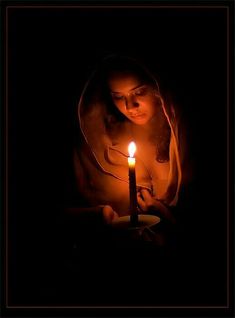 a woman holding a lit candle in her hands