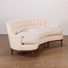 a white couch sitting on top of a floor next to a wooden frame and wall