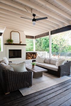 an outdoor living area with couches, tables and a fire place on the deck