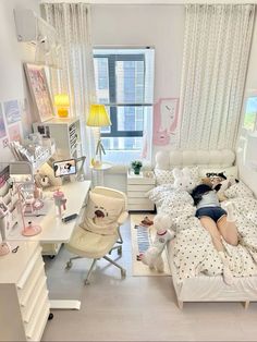 a woman laying on her bed in the middle of a room with white furniture and decor