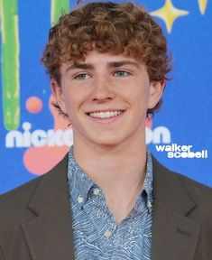 a young man with curly hair smiling at the camera