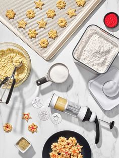 ingredients for cookies laid out on a white counter top with cookie cutters and baking utensils