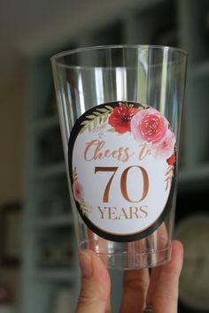 someone holding up a glass with the number seventy years on it