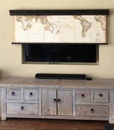 an entertainment center with drawers and a large map on the wall above it in a living room