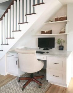 a desk with a computer on top of it under a stair case in a home office