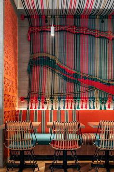 three wooden chairs sitting next to each other in front of a wall with weaving on it