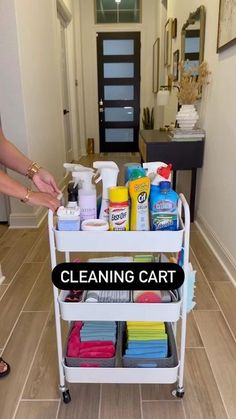 a woman is cleaning the floor with her hand on top of a cart filled with cleaning supplies