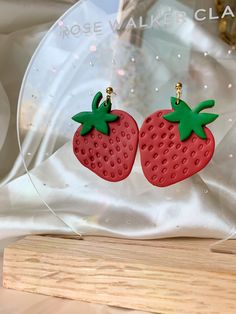 two strawberry shaped earrings sitting on top of a wooden table